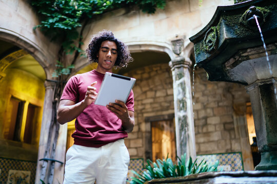 Concentrated ethnic man with tablet in courtyard