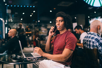Content man talking on smartphone in modern cafe