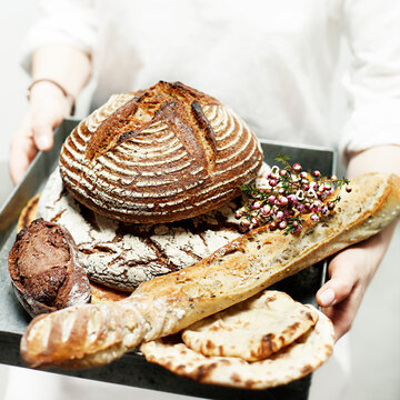 Midsection of man holding tray of breads