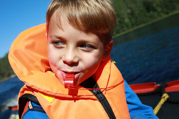 Boy with whistle in life jacket on boat