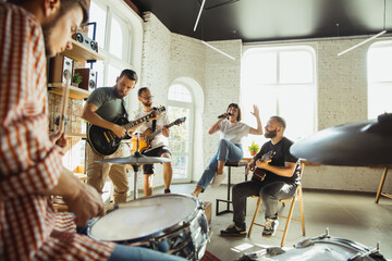 Inspiration. Musician band jamming together in art workplace with instruments. Caucasian men and...