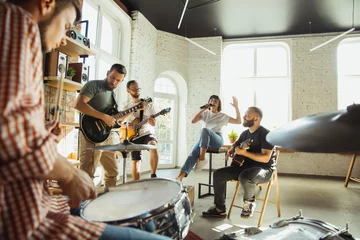 Fotobehang Inspiration. Musician band jamming together in art workplace with instruments. Caucasian men and women, musicians, playing and singing together. Concept of music, hobby, emotions, art occupation. © master1305