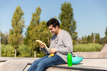 Obraz premium roller boy eating a banana sitting in a skate park