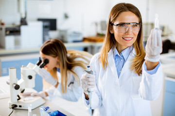 Female doctor wearing protective  face mask in lab holding flask with liquid sample