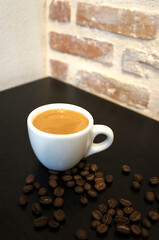 Espresso coffee in a white mug and coffee beans on the table.