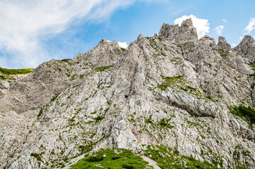 Young woman summer hiker with backpack climbing  metal cables huge limestone rock wall via ferrata. Female trekker in challenging terrain Karavanke mountains, Slovenia, Karawanken, Carinthia, Austria