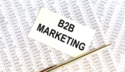 Obraz premium B2B MARKETING is on the business card. Nearby is a pen, reports and books.