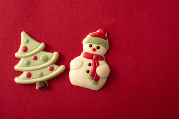 Christmas bonbons with chocolate christmas tree and snowman on red background