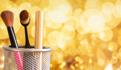 makeup brushes and mascara on gold background