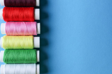 Accessories for sewing. Colored spools of thread on a blue background.