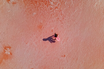 Woman walking on the surface of saline of bright pink color