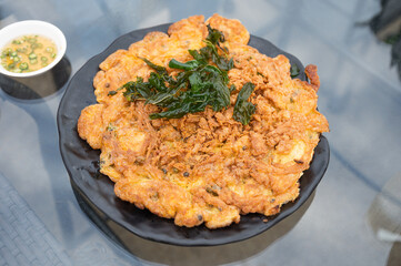 Crispy omelette with minced pork and basil leaf in black plate