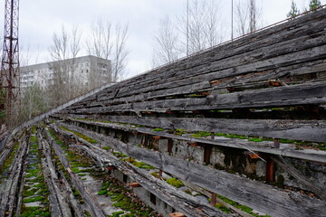 Fototapeta na wymiar The stands of an abandoned stadium in Pripyat. Old wooden benches in the stadium.