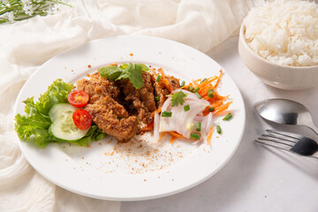 spicy chicken fried salad decorate by tomato cucumber carrot in white dish lay with rice fork spoon on white table and fabric for menu design stock photo