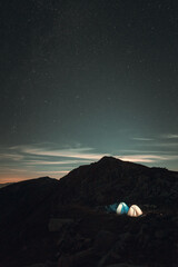 Two tents on the mountain in the night with stars