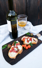 Bruschetta with sun-dried tomatoes and ricotta cheese and glass of white wine and green bottle. Cherry tomatoes. Homemade