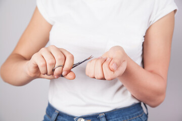 The woman cuts her nails with small scissors.