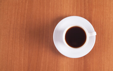 Coffee in a white cup is isolated on a wooden background.