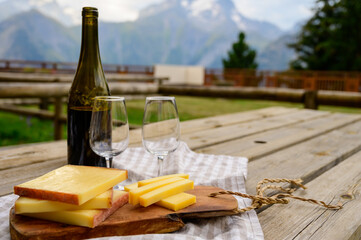 Cheese collection, French comte, beaufort or abondance cow milk cheese served outdoor with Alps mountains peaks on background