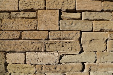 A closeup view of a weathered, sandstone brick wall.