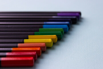 Multi-colored pencils lie on a light background. The pencils are in perfect order