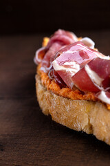 Serrano ham toast with salmorejo. Wooden background