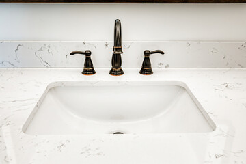 Sink in a domestic bathroom with an antique looking faucet and a marble counter