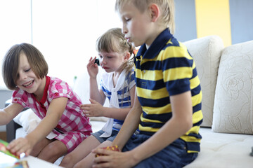 Three children play board game one girl sits and cries. How to teach child to play without tears concept