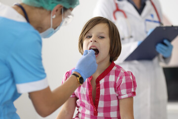 Doctor examines throat of little girl. Viral sore throat and throat diseases in children concept