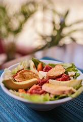 Ensalada de lechuga con tomates, pollo, palta, queso, zanahoria y queso. Vinagreta dulce. Fondo de textura turquesa