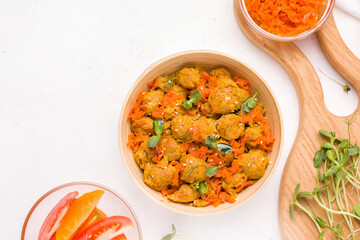 Vegan lunch with soy meat, micro greens and vegetables on a white plate. View from above. Copy space