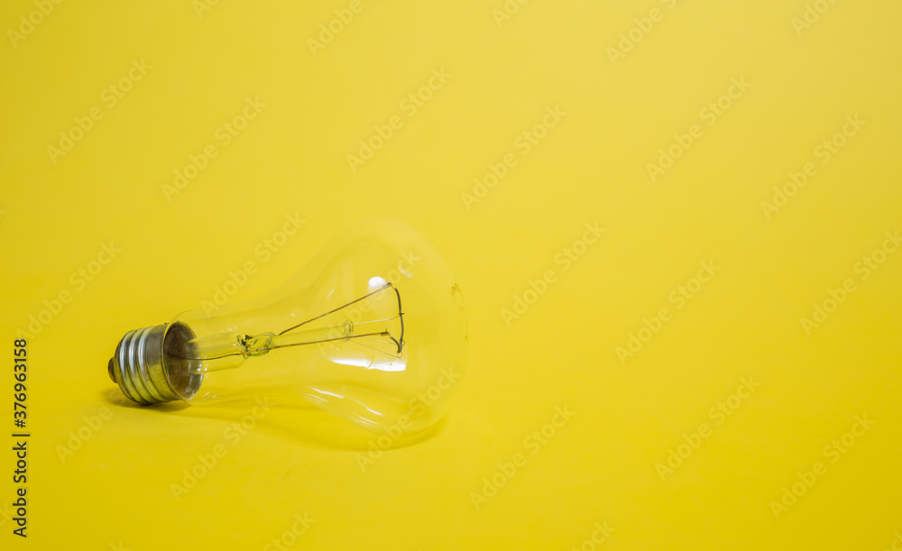 Wall mural electric transparent light bulb on a yellow background