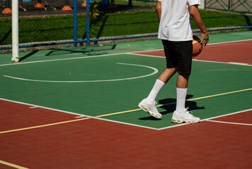 Young man on basketball court dribbling with ball