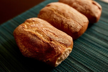 Pan ciabatta servido en una mesa de madera.  Pan recien horneado. Textura de pan sobre mantel verde.
