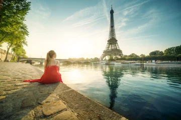 Foto op Canvas Young woman in red, looking to Eiffel tower, Paris © Iakov Kalinin