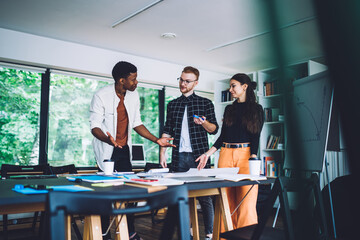 Gladful adult multiracial colleagues brainstorming in modern office
