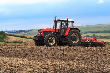 Fototapeta na wymiar Red retro tractor on the field during autumn work, on the background of the horizon
