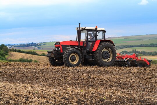 Red retro tractor on the field during autumn work, on the background of the horizon