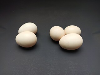 Five chicken eggs on a black background.