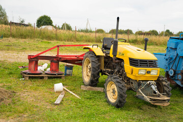 yellow tractor with red bucket stands on the grass