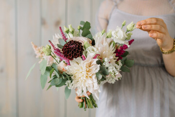 Very nice young woman holding a beautiful blossoming flower bouquet of fresh of roses many colors