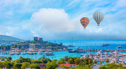 Hot air balloon flying over Saint Peter Castle (Bodrum castle) and marina, amazing white clouds in the background  - Bodrum, Turkey