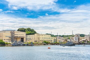 Obraz premium yokosuka, japan - july 19 2020: Support vessel Yard Tag boats of the Japan Maritime Self-Defense Force moored in front of a ready-mix Concrete factory in the Yokosuka Naval Port.