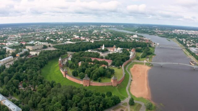 Panoramic aerial view of the Volkhov River and the old town of Veliky Novgorod, the red brick Kremlin in the rays of the setting sun and natural attractions of Russia.