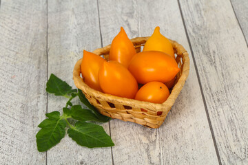 Yellow tomato heap in the wooden bowl