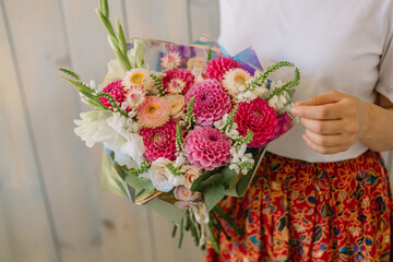 Very nice young woman holding a beautiful blossoming flower bouquet of fresh 
dahlias and roses