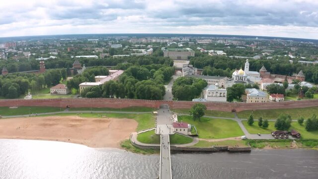 Panoramic aerial view of the Volkhov River and the old town of Veliky Novgorod, the red brick Kremlin in the rays of the setting sun and natural attractions of Russia.