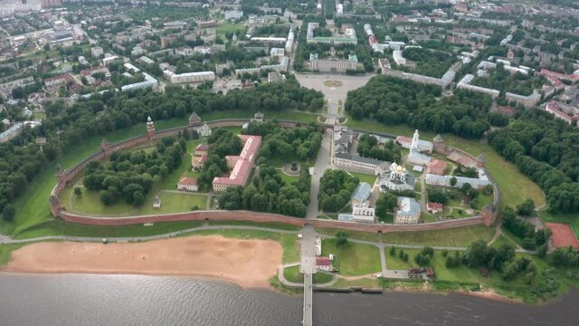 Panoramic aerial view of the Volkhov River and the old town of Veliky Novgorod, the red brick Kremlin in the rays of the setting sun and natural attractions of Russia.