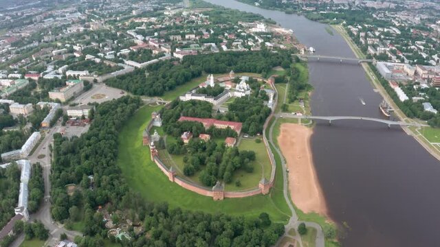 Panoramic aerial view of the Volkhov River and the old town of Veliky Novgorod, the red brick Kremlin in the rays of the setting sun and natural attractions of Russia.