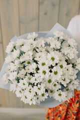 Young florist woman holding freshly made blossoming flower bouquet chamomile chrysanthemum